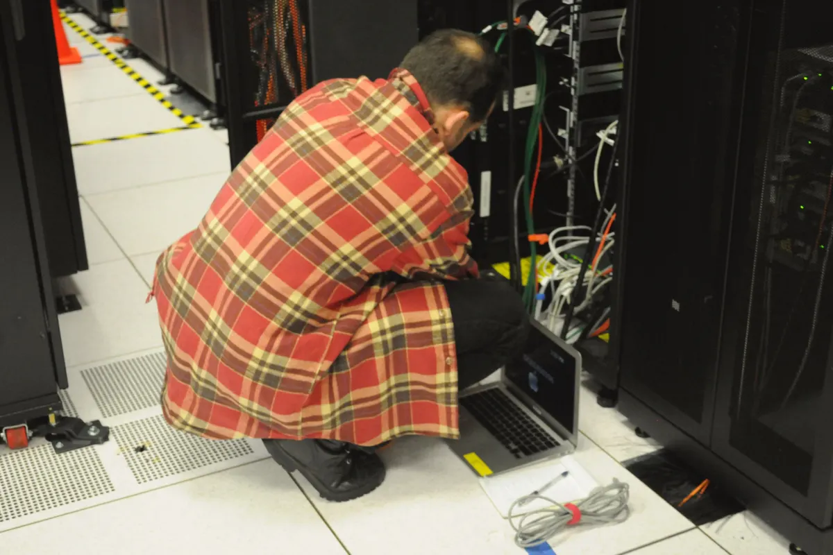 Technician inspecting a server rack with a laptop